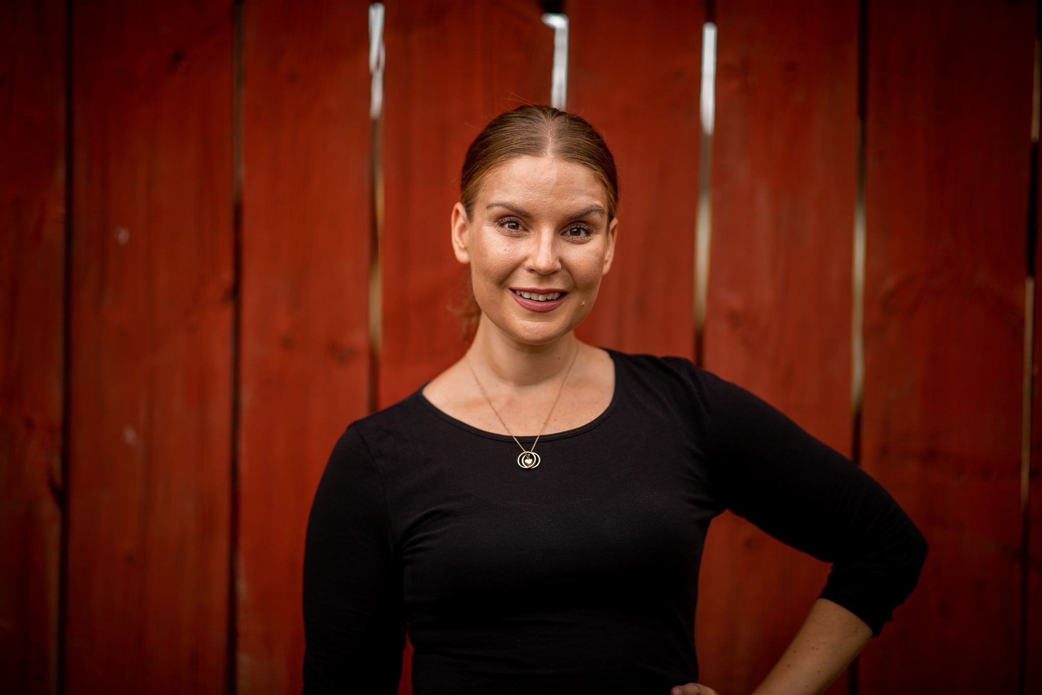 Charlotte Ström – porträtt mot röd trävägg