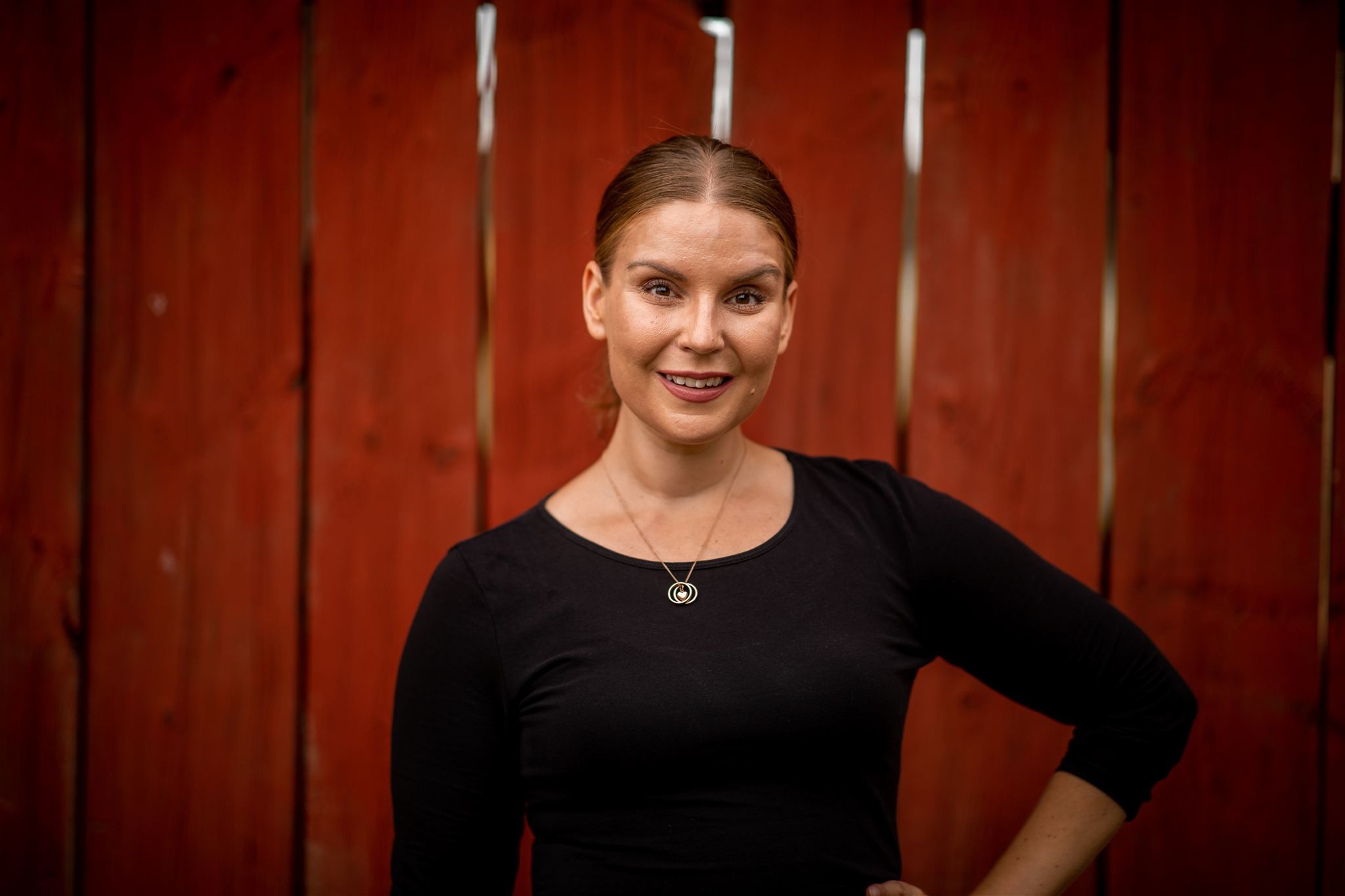 Charlotte Ström – porträtt mot röd trävägg