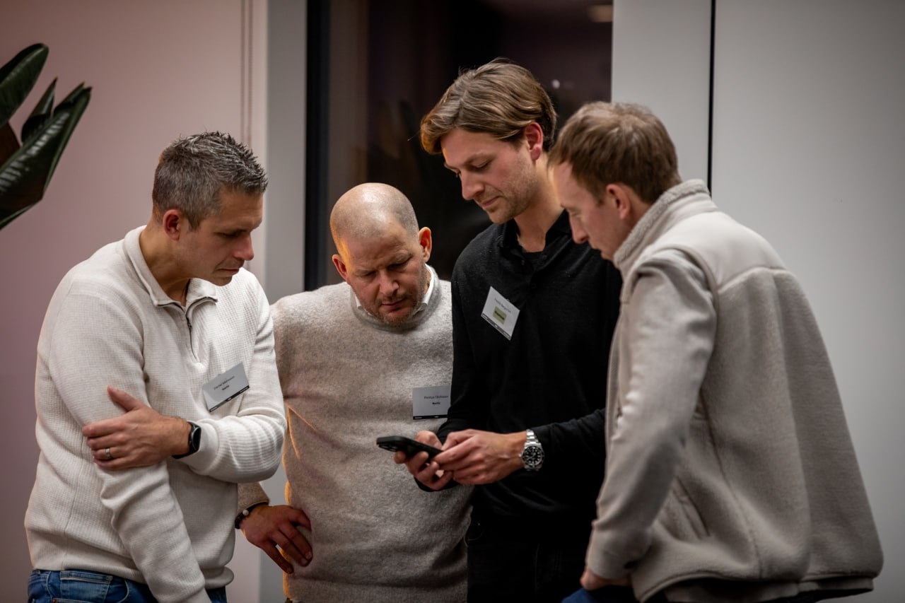 Deltagare samlas och tittar på en mobil under minglet.