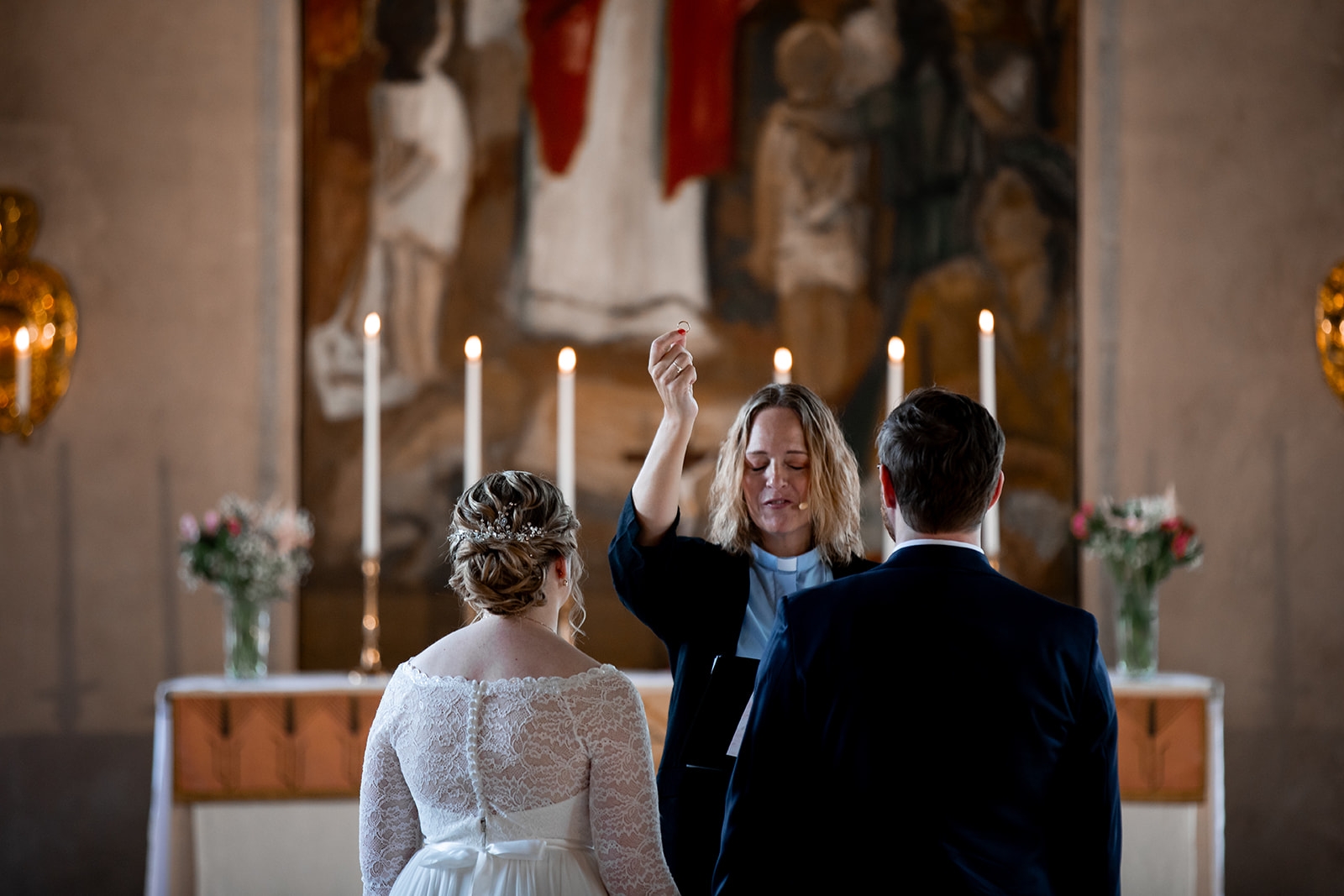 Vigsel i pampig kyrka, prästen håller upp ringen