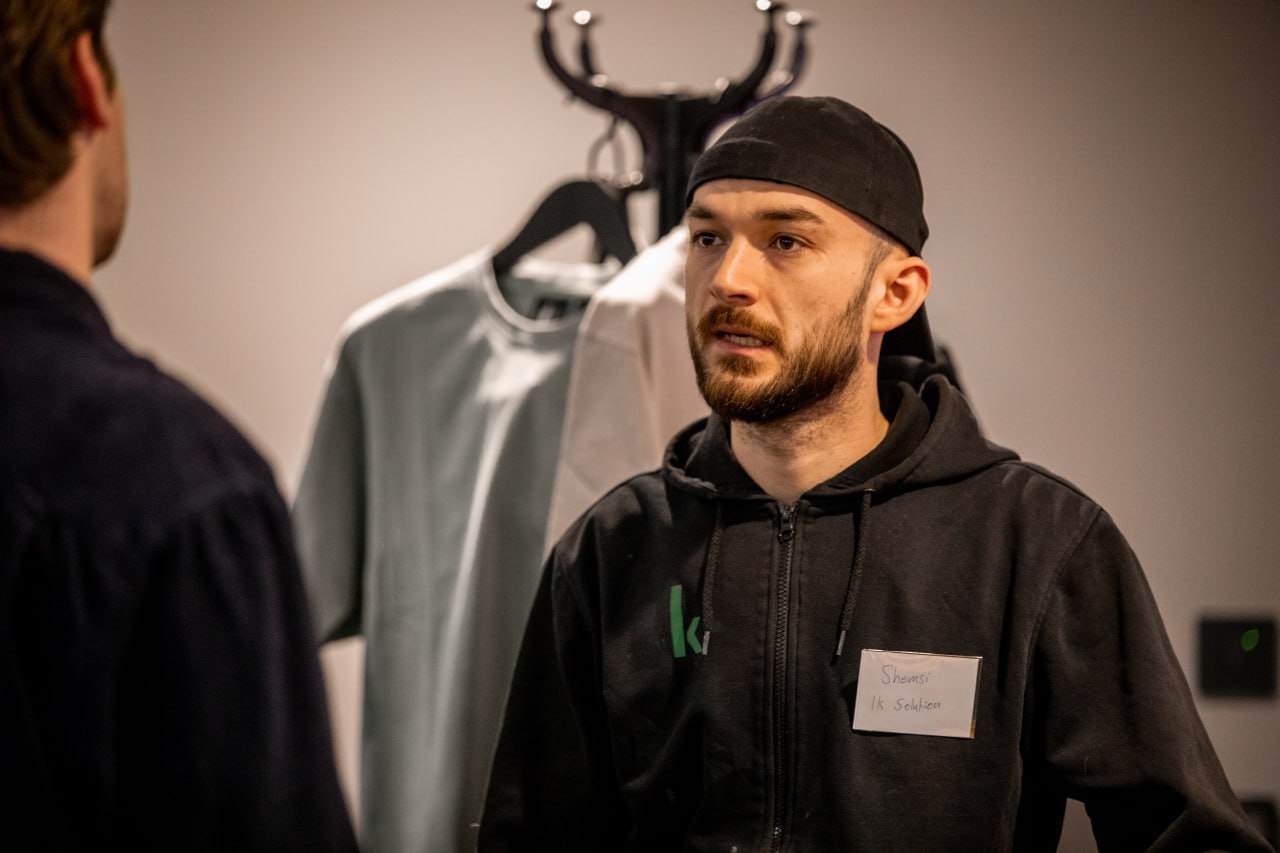 Deltagare pratar under eventet, med t-shirt-rack i bakgrunden.